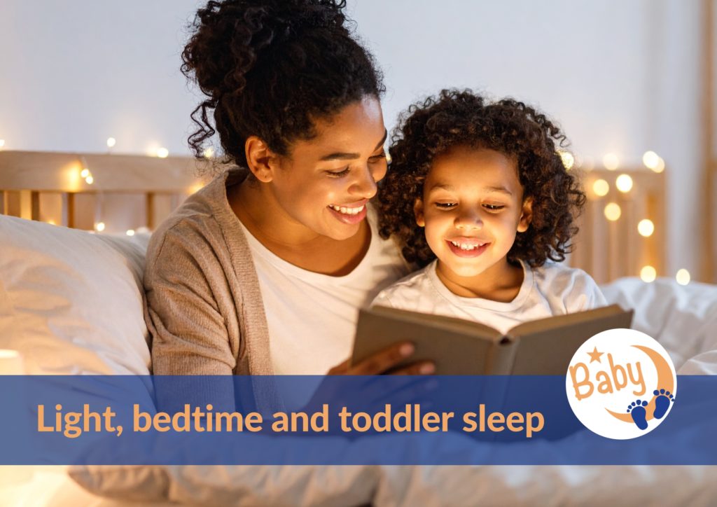 Smiling mom with her daughter reading a book in a dim light, as part of the bedtime ritual